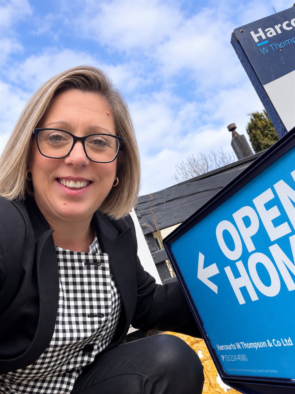 Michelle beside a Harcourts open home sign